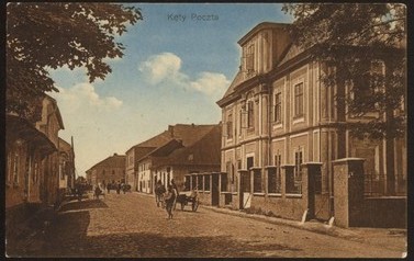 Ul. Krakowska - stara poczta | Poczt&oacute;wka przedstawia ul. Krakowską w jej przedwojennym kształcie. Na pierwszym planie stoi otoczony parkanem budynek dawnej poczty. Kiedyś był on częścią koszar dragon&oacute;w austriackich. Za nim mieściły się wojskowe stajnie. W