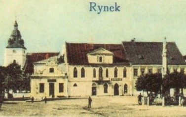 Widok Rynku z okresu pomiędzy 1910 a 1920 r. Wiadomo to stąd, że jest już murowana dzwonnica przy kościele, a dom p. Adamskich na rogu Rynku i ul. Mickiewicza nie ma jeszcze piętra. Fotografia jest złej jakości, ale za to mocno retuszowana kolorem. 