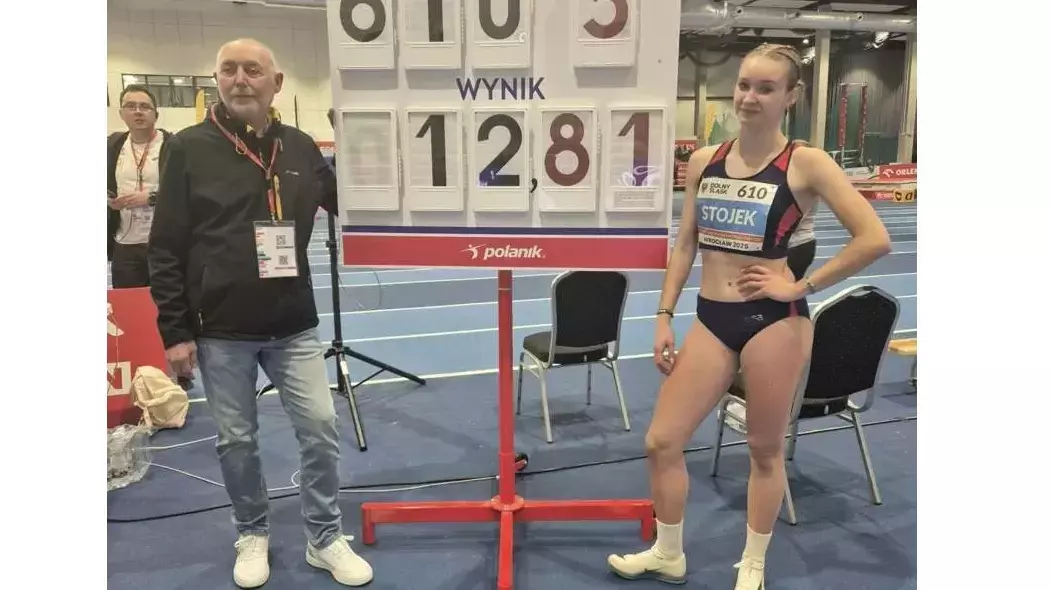 Mężczyzna i dziewczyna, ona w stroju sportowym, pozują do wspólnego zdjęcia na tle tablicy z wynikiem