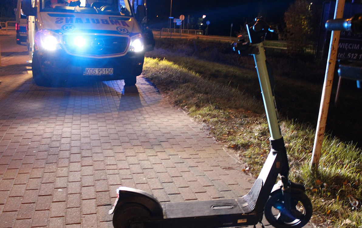 hulajnoga na pierwszym planie, noc, w tle zapalone światła radiowozu