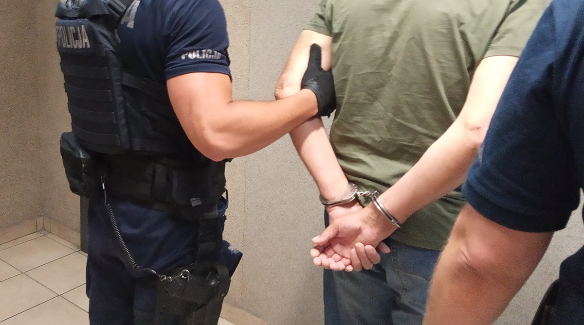 zatrzymany stoi tyłem do kadru, nie widać twarzy jego ani policjantów