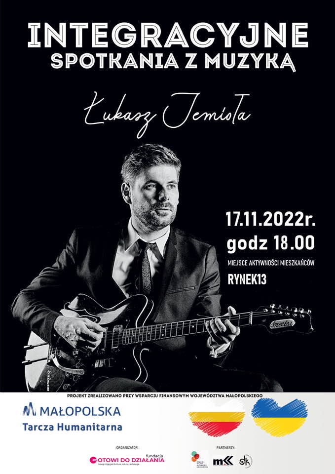 Plakat promocyjny koncertu Łukasza Jemioły, prezentujacy muzyka trzymajacego giatrę oraz napis - Łukasz Jemioła, 17 listopada 2022 r., godz. 18:00, Miejsce Aktywności Mieszkańców Rynek 13, zawierający także logotypy organizatorów i partnerów koncertu