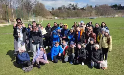 grupa uczniów pozująca do zdjęcia na tle boiska