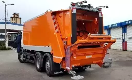 Pomarańczowy pojazd do zbierania odpadów z otwartą tylną klapą