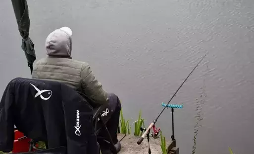 uczestnik zawodów rybackich siedzący tyłem do widza przy wędce