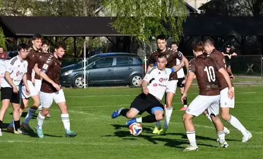 Piłkarze w trakcie gry na stadionie, podczas prób odebrania piłki zawodnikowi drużyny przeciwnej