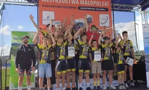 Kolarze w czarno-żółtych trykotach na scenie prezentują zdobyte medale