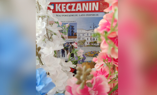 na rozmytym kwiatowym tle kęczanin widoczny zza kwiatów