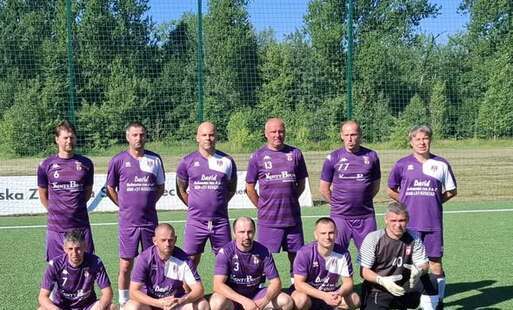 na tle lasku i stadionu pozują zawodnicy Hejnału Kęty Oldboys, ubrani w swoje charakterystyczne fioletowe stroje