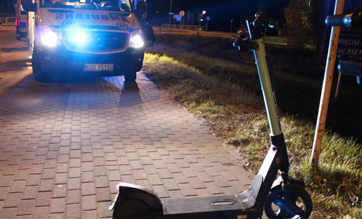 hulajnoga na pierwszym planie, noc, w tle zapalone światła radiowozu