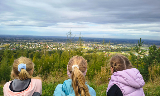 dzieci odwrócone tyłem do widza obserwują piękny krajobraz z gór - panoramę Kęt i okolic