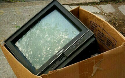 Telewizor starego typu w kartonie, wystawiony na chodniku